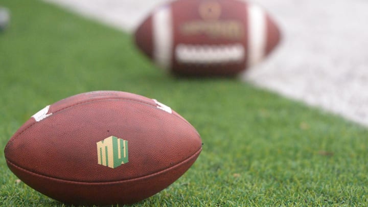 Football's on the ground during practice outside Canvas Stadium on Thursday, Aug. 1, 2019 with the Mountain West logo showing.