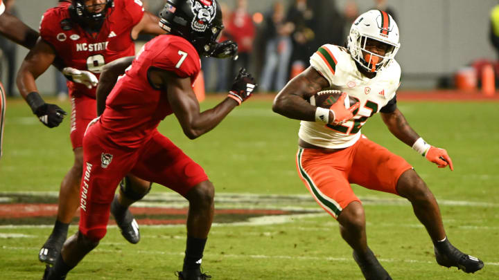 Nov 4, 2023; Raleigh, North Carolina, USA; Miami Hurricanes running back Mark Fletcher Jr. (22) runs as North Carolina State Wolfpack cornerback Shyheim Battle (7) defends during the first half at Carter-Finley Stadium. Mandatory Credit: Rob Kinnan-USA TODAY Sports