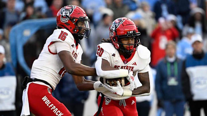 Nov 30, 2024; Chapel Hill, North Carolina, USA; North Carolina State Wolfpack quarterback CJ Bailey (16) hands the ball off to running back Hollywood Smothers (20) the ball in the first quarter at Kenan Memorial Stadium. Mandatory Credit: Bob Donnan-Imagn Images