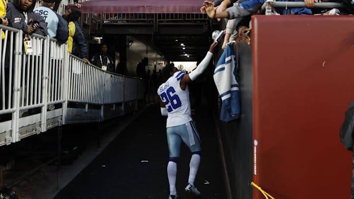 Dallas Cowboys cornerback DaRon Bland hands a piece of his equipment to a fan.