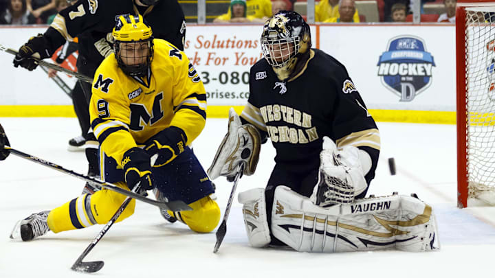 March 17, 2012; Detroit, MI, USA; Michigan Wolverines forward Luke Moffatt (9) tries to score on Western Michigan Broncos goalie Frank Slubowski (1) as Matt Tennyson (7) defends in the third period at Joe Louis Arena. 