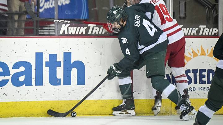 Michigan State defenseman Colin Ralph (4) and Wisconsin left wing Quinn Finley (19) collide along the boards in a game Thursday, January 15, 2026, at the Kohl Center in Madison, Wisconsin.