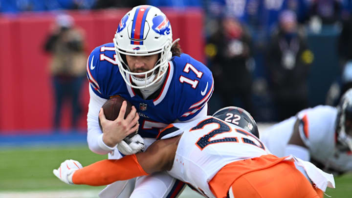 Buffalo Bills quarterback Josh Allen (17) is tackled by Denver Broncos safety Brandon Jones (22) during the first quarter in an AFC wild card game at Highmark Stadium.