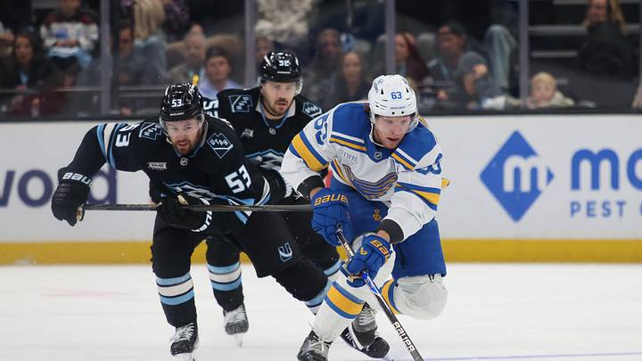Apr 16, 2026; Salt Lake City, Utah, USA; St. Louis Blues left wing Jake Neighbours (63) skates with the puck against Utah Mammoth left wing Michael Carcone (53) during the second period at Delta Center. Mandatory Credit: Rob Gray-Imagn Images