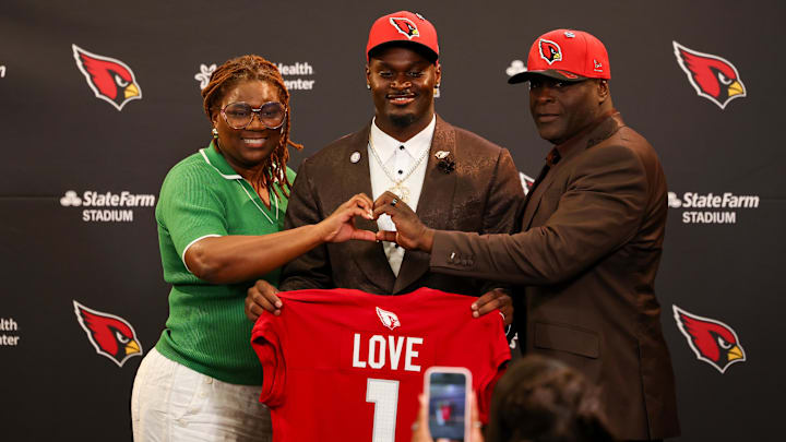 Apr 24, 2026; Phoenix, AZ, USA; Arizona Cardinals first-round draft pick Jeremiyah Love poses with his jersey and his parents during a press conference at Dignity Health Arizona Cardinals Training Center. Mandatory Credit: Anna Carrington-Imagn Images