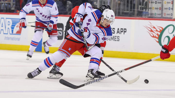 Apr 5, 2025; Newark, New Jersey, USA; New York Rangers right wing Gabe Perreault (94) battles for the puck against the New Jersey Devils during the first period at Prudential Center. Mandatory Credit: Ed Mulholland-Imagn Images