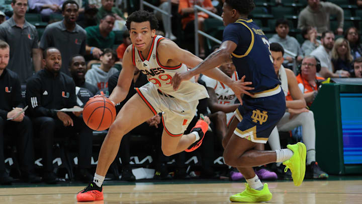 Feb 1, 2025; Coral Gables, Florida, USA; Miami Hurricanes guard Divine Ugochukwu (99) drives to the basket past Notre Dame Fighting Irish guard Markus Burton (3) during the second half at Watsco Center. Mandatory Credit: Sam Navarro-Imagn Images