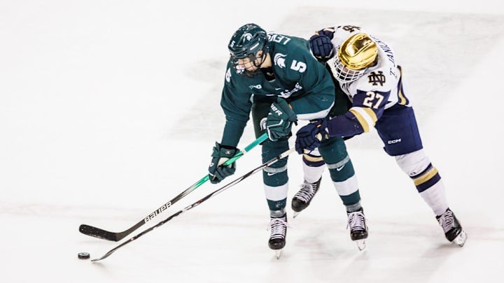 Michigan State defenseman Artyom Levshunov (5) and Notre Dame forward Trevor Janicke (27) battle for the puck during the Michigan State-Notre Dame NCAA hockey game on Friday, February 02, 2024, at Compton Family Ice Arena in South Bend, Indiana.