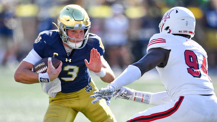 Sep 21, 2024; South Bend, Indiana, USA; Notre Dame Fighting Irish quarterback Riley Leonard (13) runs the ball as Miami Redhawks defensive end Josh Lukusa (94) defends in the second quarter at Notre Dame Stadium. Mandatory Credit: Matt Cashore-Imagn Images Sep 21, 2024; South Bend, Indiana, USA; Notre Dame Fighting Irish quarterback Riley Leonard (13) runs the ball as Miami Redhawks defensive end Josh Lukusa (94) defends in the second quarter at Notre Dame Stadium. Mandatory Credit: Matt Cashore-Imagn Images
