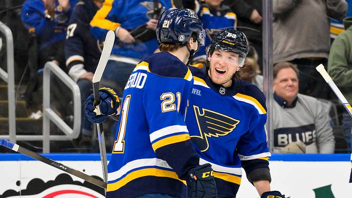 Apr 3, 2025; St. Louis, Missouri, USA;  St. Louis Blues right wing Jimmy Snuggerud (21) celebrates after assisting on a goal by left wing Jake Neighbours (63) for his first NHL point during the third period against the Pittsburgh Penguins at Enterprise Center. Mandatory Credit: Jeff Curry-Imagn Images