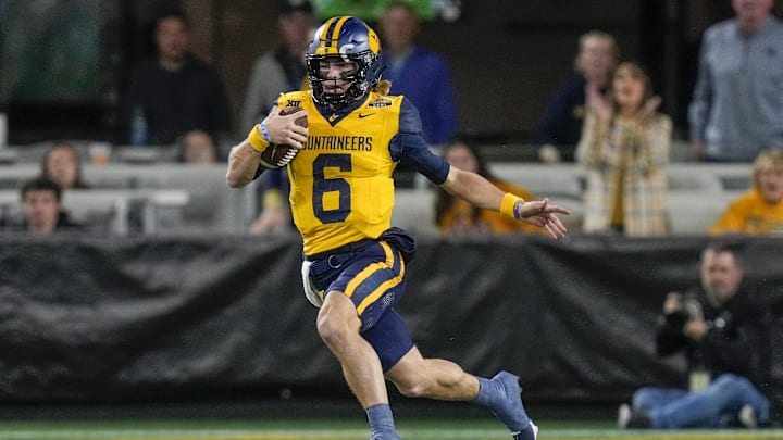 Dec 27, 2023; Charlotte, NC, USA; West Virginia Mountaineers quarterback Garrett Greene (6) runs the ball against the North Carolina Tar Heels during the first half at Bank of America Stadium. Mandatory Credit: Jim Dedmon-USA TODAY Sports