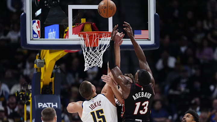 Nov 5, 2025; Denver, Colorado, USA; Miami Heat center Bam Adebayo (13) and Denver Nuggets center Nikola Jokic (15) reach for the rebound in the first quarter at Ball Arena. Mandatory Credit: Ron Chenoy-Imagn Images