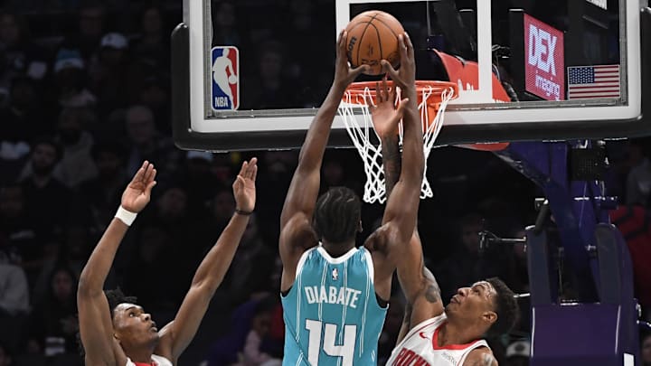 Dec 23, 2024; Charlotte, North Carolina, USA;  Charlotte Hornets forward Moussa Diabate (14) drives in past Houston Rockets guard forward Amen Thompson (1) and forward Jabari Smith Jr. (10) during the second half at the Spectrum Center. Mandatory Credit: Sam Sharpe-Imagn Images