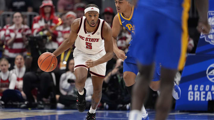 Mar 11, 2026; Charlotte, NC, USA; NC State Wolfpack guard Tre Holloman (5) dribbles past Pittsburgh Panthers forward Roman Siulepa (13) during the first half at Spectrum Center. Mandatory Credit: Jim Dedmon-Imagn Images Mar 11, 2026; Charlotte, NC, USA; NC State Wolfpack guard Tre Holloman (5) dribbles past Pittsburgh Panthers forward Roman Siulepa (13) during the first half at Spectrum Center. Mandatory Credit: Jim Dedmon-Imagn Images