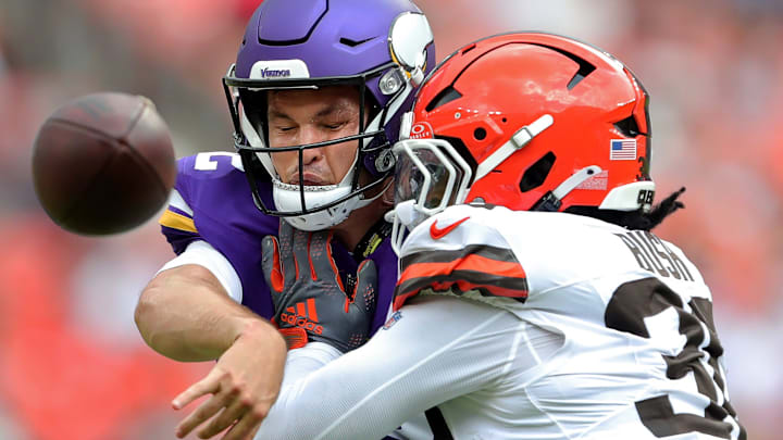 Minnesota Vikings quarterback Nick Mullens (12) takes a hit while throwing from Cleveland Browns linebacker Devin Bush (30) during the first half of an NFL preseason football game at Cleveland Browns Stadium, Saturday, Aug. 17, 2024, in Cleveland, Ohio.