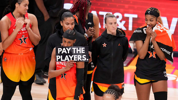 Washington Mystics' Brittney Sykes (20) holds up a sign as Minnesota Lynx's Napheesa Collier (24) is interviewed Saturday, July 19, 2025, during the WNBA All-Star Game at Gainbridge Fieldhouse in Indianapolis.