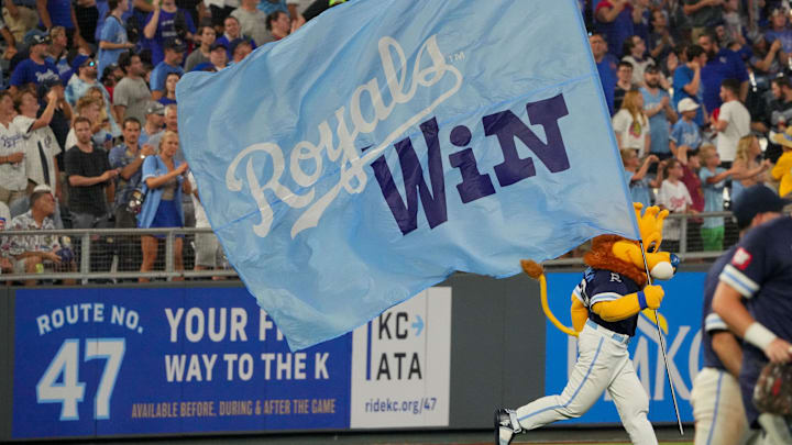 Jul 26, 2024; Kansas City, Missouri, USA; The Kansas City Royals mascot Sluggerrr runs on field with a large sign after the win over the Chicago Cubs at Kauffman Stadium. Mandatory Credit: Denny Medley-Imagn Images Jul 26, 2024; Kansas City, Missouri, USA; The Kansas City Royals mascot Sluggerrr runs on field with a large sign after the win over the Chicago Cubs at Kauffman Stadium. Mandatory Credit: Denny Medley-Imagn Images