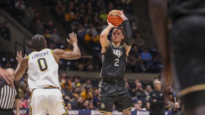 Mar 6, 2026; Morgantown, West Virginia, USA; UCF Knights guard Riley Kugel (2) shoots a three pointer over West Virginia Mountaineers forward Brenen Lorient (0) during the first half at Hope Coliseum. Mandatory Credit: Ben Queen-Imagn Images