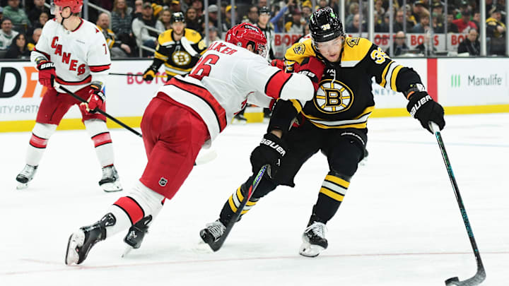 Apr 5, 2025; Boston, Massachusetts, USA; Boston Bruins center Morgan Geekie (39) tries to control the puck from Carolina Hurricanes defenseman Sean Walker (26) during the third period at TD Garden. Mandatory Credit: Bob DeChiara-Imagn Images
