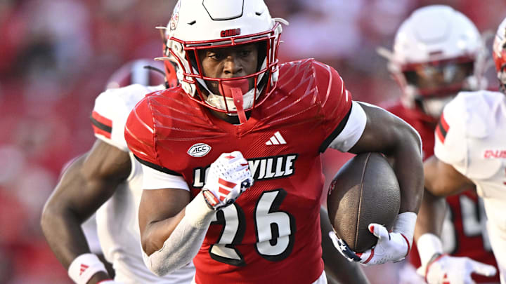 Sep 7, 2024; Louisville, Kentucky, USA;  Louisville Cardinals running back Duke Watson (26) runs the ball against Jacksonville State Gamecocks safety Austin Ambush (21) during the second half at L&N Federal Credit Union Stadium. 