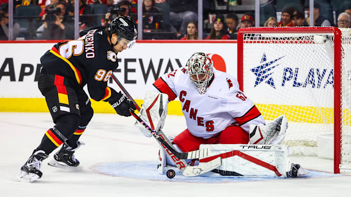 Oct 24, 2024; Calgary, Alberta, CAN; Carolina Hurricanes goaltender Pyotr Kochetkov (52) makes a save against Calgary Flames left wing Andrei Kuzmenko (96) during the third period at Scotiabank Saddledome. Mandatory Credit: Sergei Belski-Imagn Images