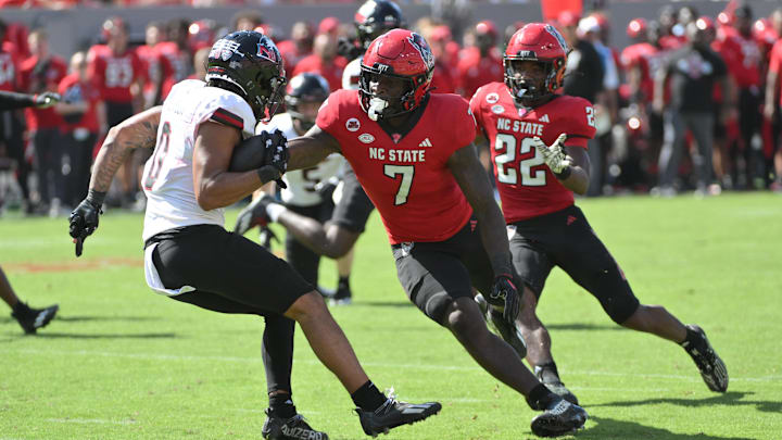 Sep 28, 2024; Raleigh, North Carolina, USA; Northern Illinois Huskies wide receiver Cam Thompson (0) dodges North Carolina State Wolfpack saftey Bishop Fitzgerald (7) at Carter-Finley Stadium. Mandatory Credit: Zachary Taft-Imagn Images