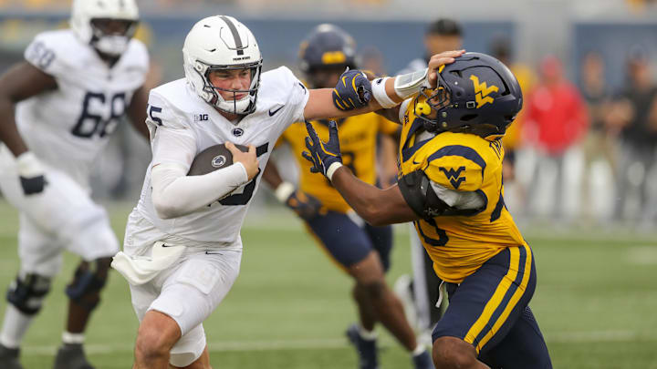 Aug 31, 2024; Morgantown, West Virginia, USA; Penn State Nittany Lions quarterback Drew Allar (15) runs the ball and stiff arms West Virginia Mountaineers linebacker Josiah Trotter (40) during the fourth quarter at Mountaineer Field at Milan Puskar Stadium.