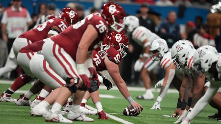 Dec 28, 2023; San Antonio, TX, USA; Helmets at the line of scrimmage as Oklahoma Sooners offensive lineman Troy Everett (52) snaps the ball against the Arizona Wildcats in the fist half of the Alamo Bowl at Alamodome. Mandatory Credit: Kirby Lee-Imagn Images