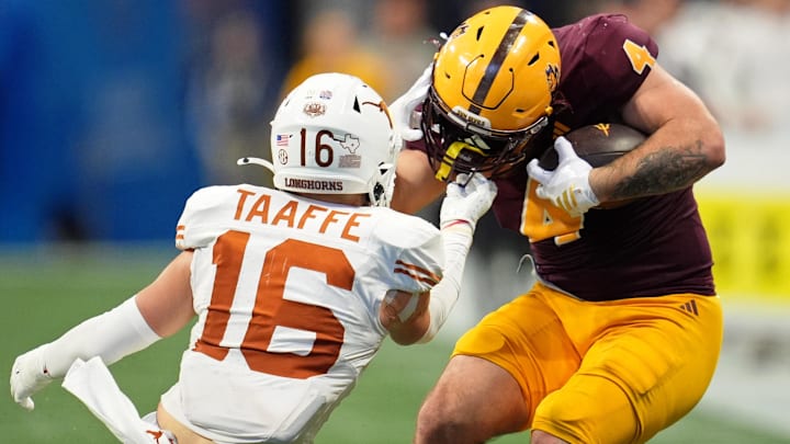 Texas Longhorns defensive back Michael Taaffe (16) pulls on the helmet of Arizona State Sun Devils running back Cam Skattebo (4) during the second half of the Peach Bowl.