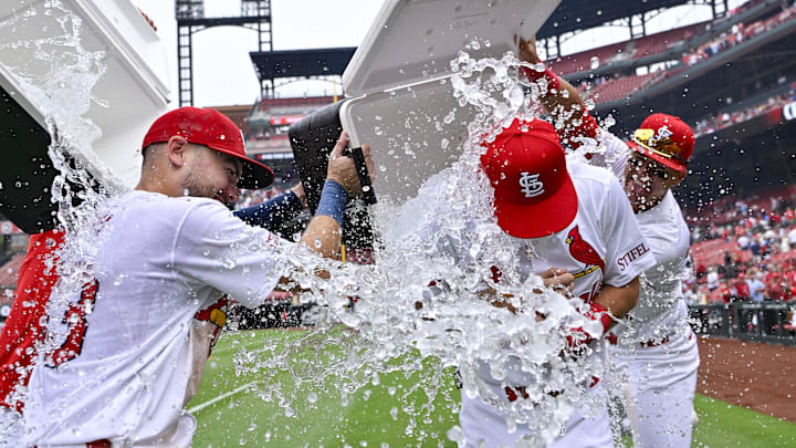 Sep 12, 2024; St. Louis, Missouri, USA;  St. Louis Cardinals second baseman Thomas Saggese (25) is doused with water by center fielder Michael Siani (63) and left fielder Lars Nootbaar (21) after collecting his first career hit and his first rbi in a victory over the Cincinnati Reds at Busch Stadium. Mandatory Credit: Jeff Curry-Imagn Images