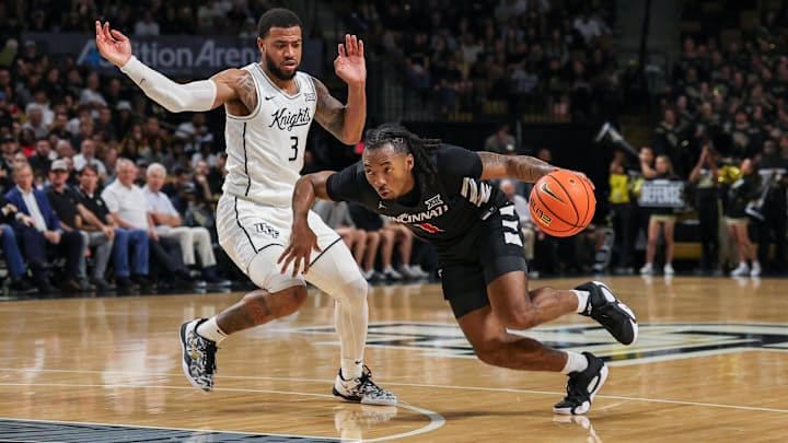 Feb 5, 2025; Orlando, Florida, USA; Cincinnati Bearcats guard Day Day Thomas (1) drives past UCF Knights guard Darius Johnson (3) during the first half at Addition Financial Arena. Mandatory Credit: Mike Watters-Imagn Images