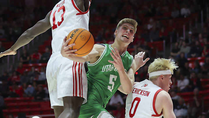 Dec 16, 2023; Salt Lake City, Utah, USA; Utah Valley Wolverines guard Tanner Toolson (5) drives to the basket between Utah Utes center Keba Keita (13) and guard Hunter Erickson (0) during the first half at Jon M. Huntsman Center. Mandatory Credit: Rob Gray-Imagn Images