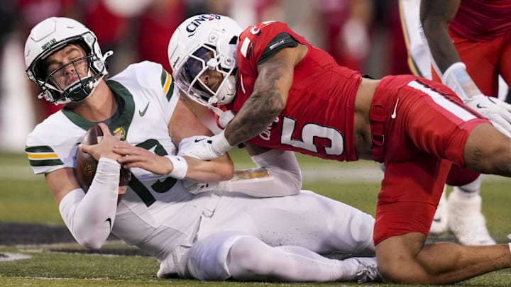 Oct 25, 2025; Cincinnati, Ohio, USA;  Baylor Bears quarterback Sawyer Robertson (13) runs with the ball as he is tackled Cincinnati Bearcats safety Christian Harrison (5) in the second half at Nippert Stadium. Mandatory Credit: Aaron Doster-Imagn Images