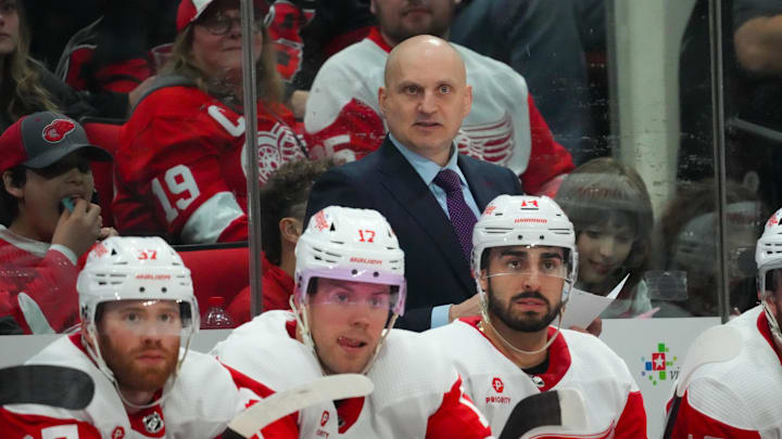 Mar 28, 2024; Raleigh, North Carolina, USA;  Detroit Red Wings head coach Derek Lalonde looks on from behind the bench against the Carolina Hurricanes during the second period at PNC Arena. Mandatory Credit: James Guillory-Imagn Images