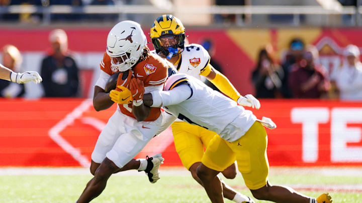 Texas Longhorns wide receiver Ryan Wingo runs with the ball after a catch while Michigan Wolverines defensive back TJ Metcalf tackles during the first half at Camping World Stadium. Texas Longhorns wide receiver Ryan Wingo runs with the ball after a catch while Michigan Wolverines defensive back TJ Metcalf tackles during the first half at Camping World Stadium.
