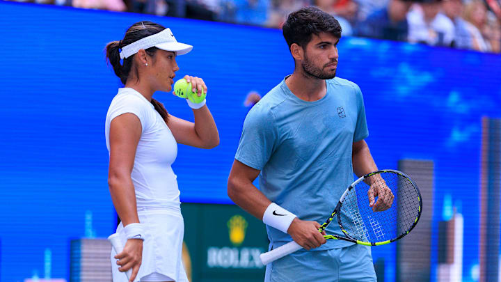 August 19, 2025; Emma Raducanu and Carlos Alcaraz talk strategy during a mixed doubles match against Jessica Pegula and Jack Draper at the 2025 US Open at USTA Billie Jean King National Tennis Center.