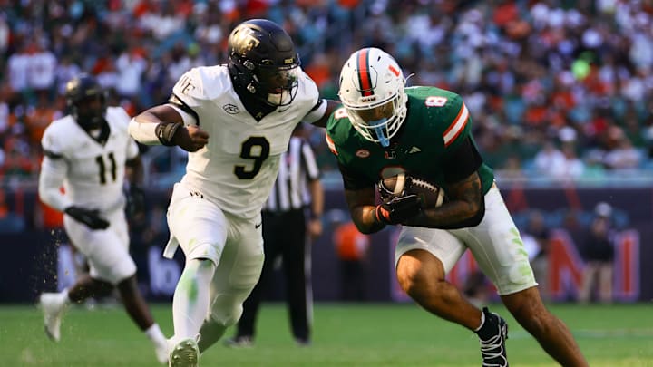 Nov 23, 2024; Miami Gardens, Florida, USA; Miami Hurricanes tight end Elijah Arroyo (8) runs with the football as Wake Forest Demon Deacons linebacker Quincy Bryant (9) attempts a tackle during the second quarter at Hard Rock Stadium. Mandatory Credit: Sam Navarro-Imagn Images