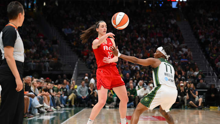 Jun 24, 2025; Seattle, Washington, USA; Indiana Fever guard Caitlin Clark (22) passes the ball over Seattle Storm guard Erica Wheeler (17) during the second half at Climate Pledge Arena. Mandatory Credit: Steven Bisig-Imagn Images