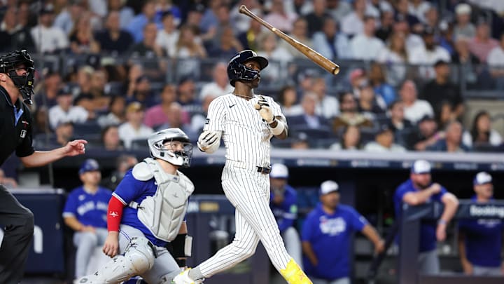 A baseball player at the plate wearing a white uniform after throwing the tan baseball bat into the air A baseball player at the plate wearing a white uniform after throwing the tan baseball bat into the air