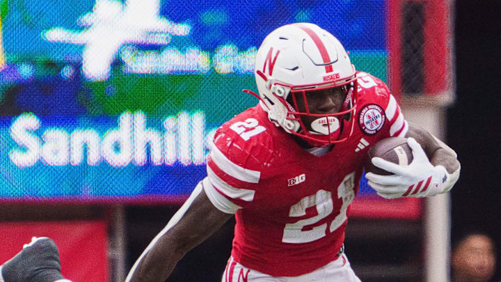 Oct 25, 2025; Lincoln, Nebraska, USA; Nebraska Cornhuskers running back Emmett Johnson (21) runs with the ball against Northwestern Wildcats defensive lineman Carmine Bastone (1) during the third quarter at Memorial Stadium. 