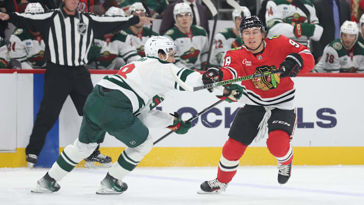 Oct 3, 2025; Chicago, Illinois, USA; Chicago Blackhawks center Connor Bedard (98) and Minnesota Wild defenseman Zeev Buium (8) battle for control of the puck during the first period at United Center. Mandatory Credit: Talia Sprague-Imagn Images