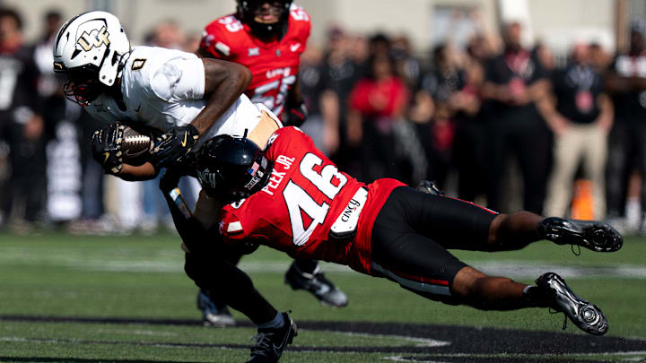 Cincinnati Bearcats defensive back Antwan Peek Jr. (46) tackles UCF Knights tight end Dylan Wade (0) in the first quarter of the NCAA football game between the Cincinnati Bearcats and UCF Knights at Nippert Stadium in Cincinnati on Oct. 11, 2025. Cincinnati Bearcats defensive back Antwan Peek Jr. (46) tackles UCF Knights tight end Dylan Wade (0) in the first quarter of the NCAA football game between the Cincinnati Bearcats and UCF Knights at Nippert Stadium in Cincinnati on Oct. 11, 2025.