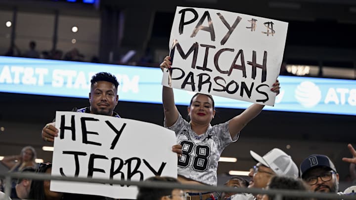 Dallas Cowboys fans hold up signs to owner Jerry Jones and defensive end Micah Parsons.