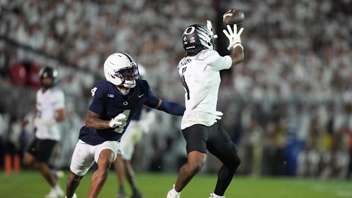 Sep 27, 2025; University Park, Pennsylvania, USA; Oregon Ducks wide receiver Dakorien Moore (1) makes a catch past Penn State Nittany Lions cornerback A.J. Harris (4) during the fourth quarter at Beaver Stadium. Mandatory Credit: James Lang-Imagn Images