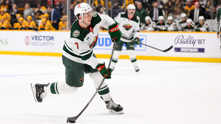 Jan 18, 2025; Nashville, Tennessee, USA;  Minnesota Wild defenseman Brock Faber (7) takes a shot on goal against the Nashville Predators during the second period at Bridgestone Arena. Mandatory Credit: Steve Roberts-Imagn Images