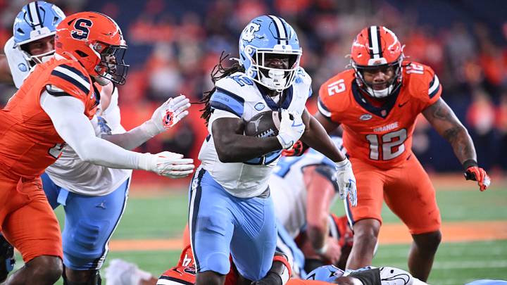 Oct 31, 2025; Syracuse, New York, USA; North Carolina Tar Heels running back Demon June (12) runs between Syracuse Orange linebacker David Reese (left) and linebacker Anwar Sparrow (12) in the third quarter at the JMA Wireless Dome. Mandatory Credit: Mark Konezny-Imagn Images
