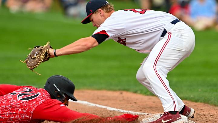  Khadim Diaw of Orleans dives back to first ahead of the tag by Easton Carmichael. Credit: Cape League baseballRon Schloerb/Cape Cod Times