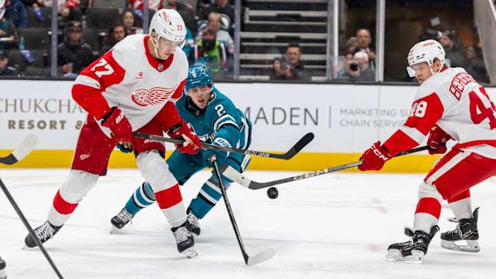 Nov 18, 2024; San Jose, California, USA; Detroit Red Wings defenseman Simon Edvinsson (77) and San Jose Sharks center Will Smith (2) fight for the puck during the second period at SAP Center at San Jose. Mandatory Credit: Bob Kupbens-Imagn Images