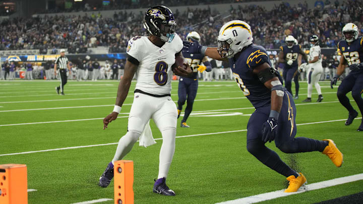 Baltimore Ravens quarterback Lamar Jackson (8) scores on a 10-yard touchdown run against Los Angeles Chargers linebacker Daiyan Henley (0) in the first half at SoFi Stadium.
