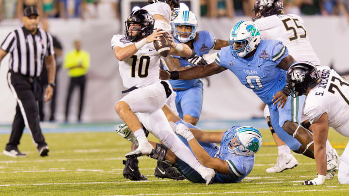 Dec 3, 2022; New Orleans, Louisiana, USA; UCF Knights quarterback John Rhys Plumlee (10) scrambles away from Tulane Green Wave defensive lineman Patrick Jenkins (0) during the second half at Yulman Stadium. Dec 3, 2022; New Orleans, Louisiana, USA; UCF Knights quarterback John Rhys Plumlee (10) scrambles away from Tulane Green Wave defensive lineman Patrick Jenkins (0) during the second half at Yulman Stadium.